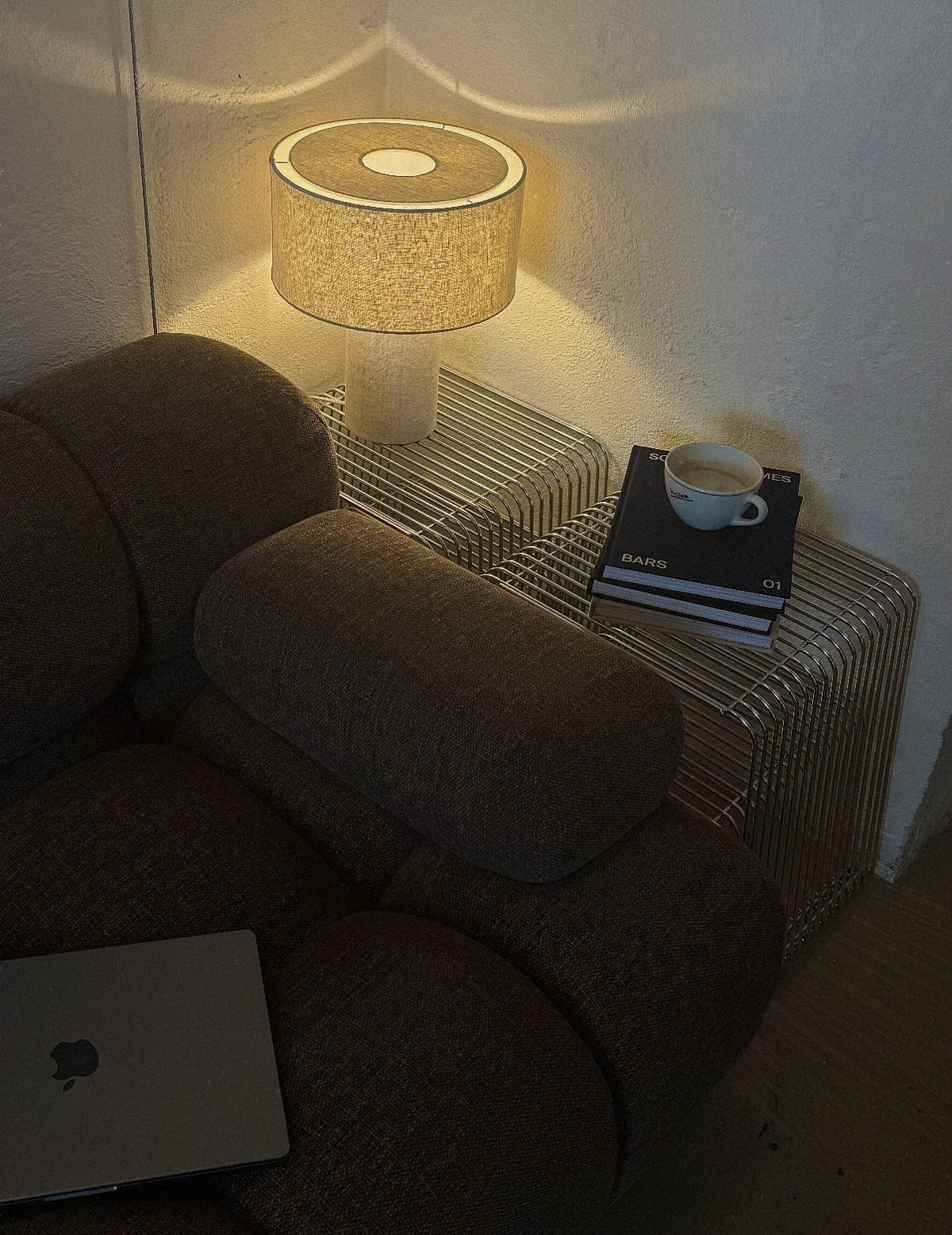 Varmt lampelys, kaffe og bøger ved en sofa
