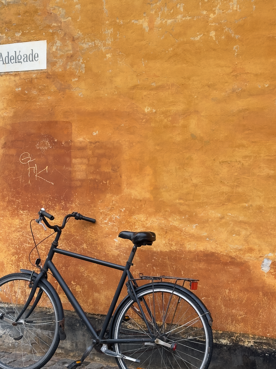 Sort cykel foran en orange facade i Adelgade
