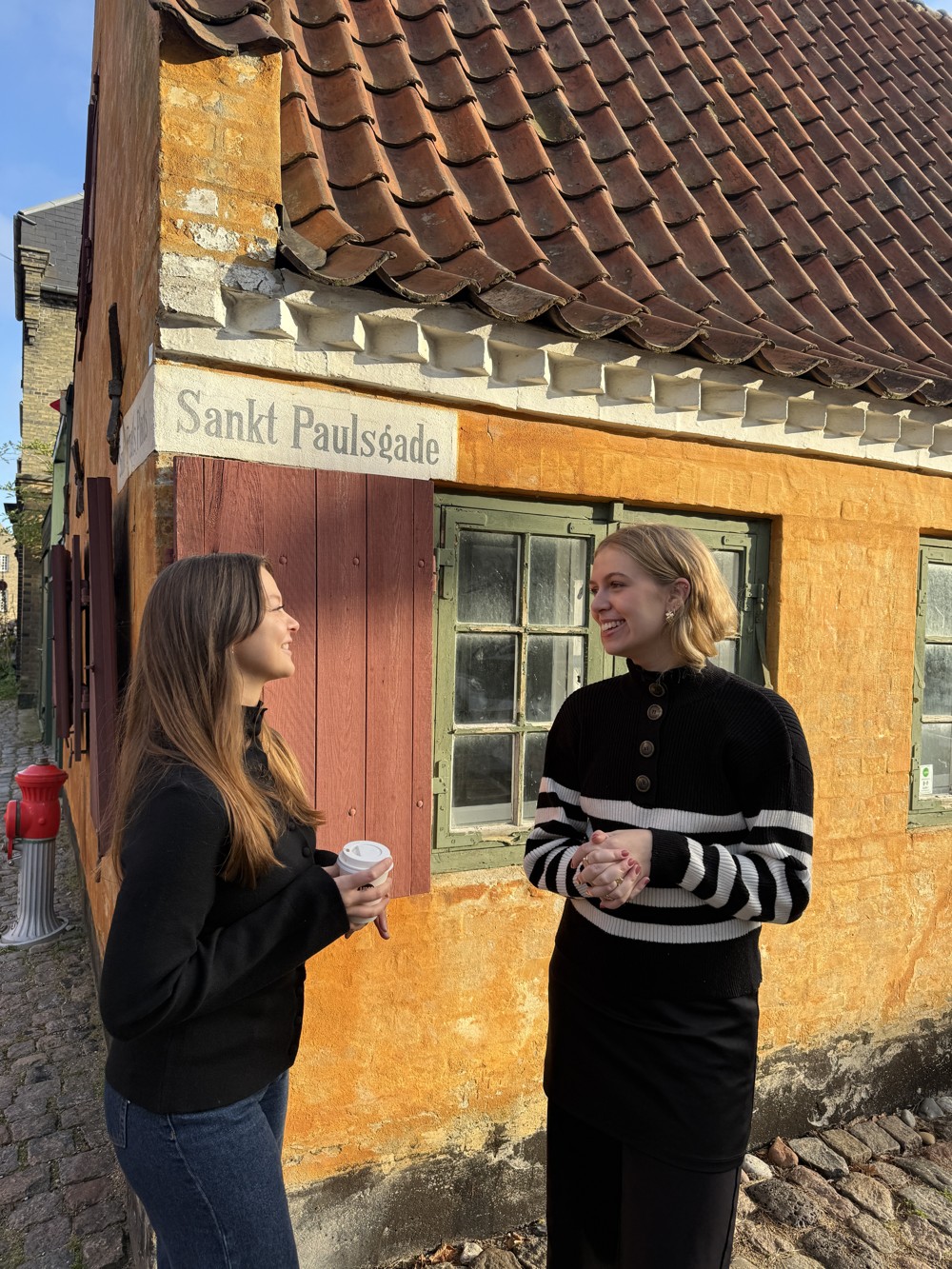 To kolleger i samtale foran en orange facade i Nyboder